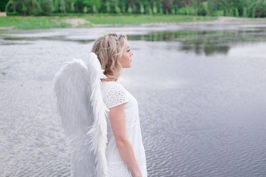 portrait of blonde woman in white dress and white angels wings. good people. heaven, god. paradise angel.