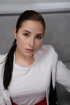 sexy business woman sitting by the table on couch in grey room - office. big boss. important, confident women. femininity. millennials.