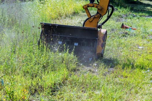 Wheeled tractor lawn mower with a external detachable mounted mower equipment driving on roadside of a suburban highway road maintenance service mechanization machine