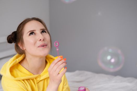 woman in yellow among soap bubbles on grey background.