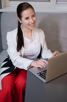brunette woman use laptop in grey room. freelancer. working from home. student, remote study.