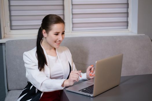 brunette woman use laptop in grey room. freelancer. working from home. student, remote study.