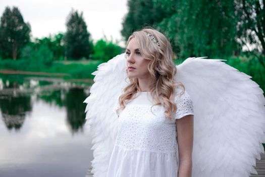 portrait of blonde woman in white dress and white angels wings. good people. heaven, god. paradise angel.