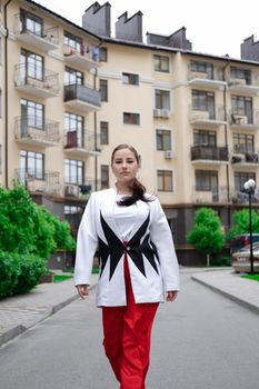confident brunette woman in red pants and white blouse and jacket walking in the street.