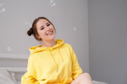 woman in yellow among soap bubbles on grey background.
