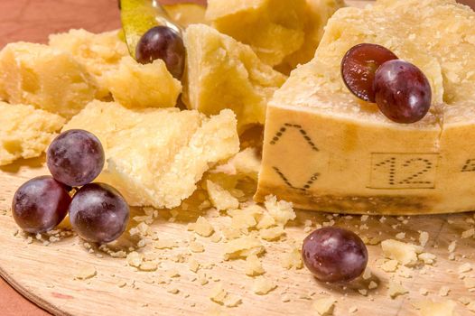 Parmesan cheese with grape on wooden board