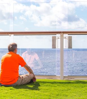 Man sitting on real grass lawn on cruise ship