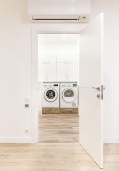 White opened door in modern home with air conditioner and wooden floor