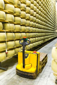 Parmigiano Cheese factory production shelves with aging cheese in Italy, Bologna