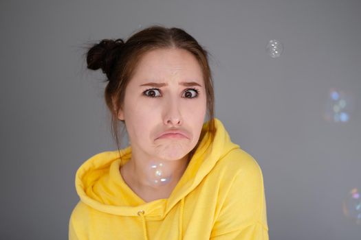 woman in yellow among soap bubbles on grey background.