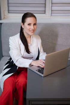 brunette woman use laptop in grey room. freelancer. working from home. student, remote study.