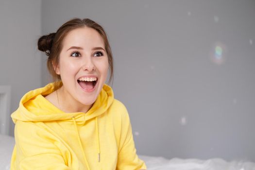 happy positive brunette in yellow hoodie in bright room. happy people. millennial generation. fashionable teenager. trendy colours.