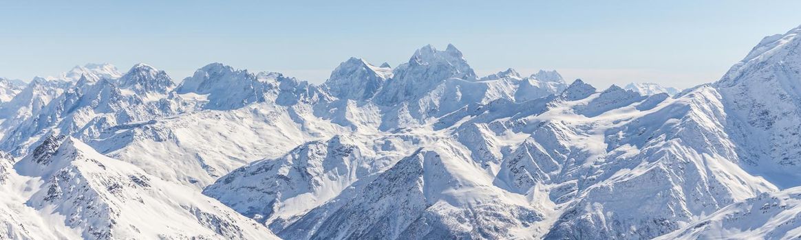 White snowy winter Caucasus mountains at sunny day. Panorama view from ski slope Elbrus, Russia with sky background