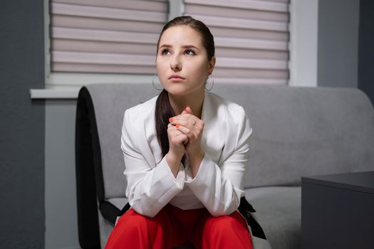 sexy business woman sitting by the table on couch in grey room - office. big boss. important, confident women. femininity. millennials.