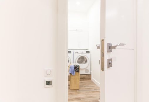 View through door to laundry room with basket and washing machine