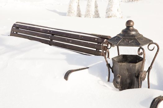 Wooden bench covered with snow in a winter park