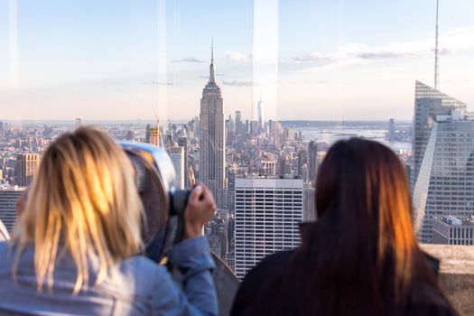 New york, USA - May 17, 2019: Rear View of Woman Peering Through Binocular View Finder at New York City Skyline from Top of the Rock