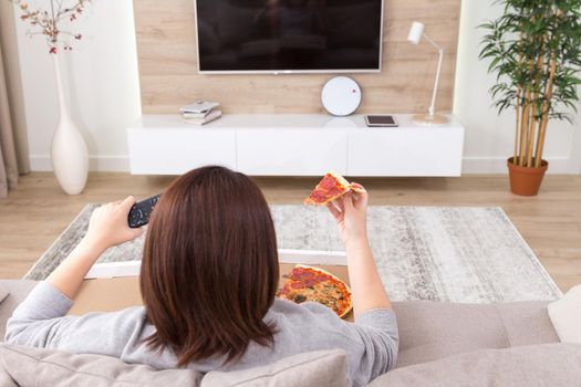 Girl eating pizza and watching tv