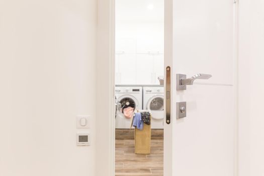 View through door to laundry room with basket and washing machine