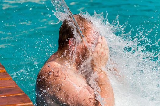 Stream of water splash on Man head in swimming pool