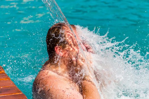 Stream of water splash on Man head in swimming pool