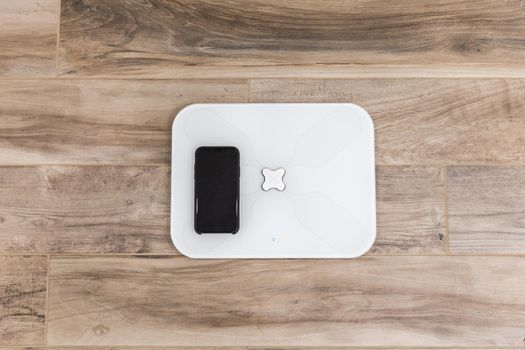 Smart scale standing on a floor connected to smartphone