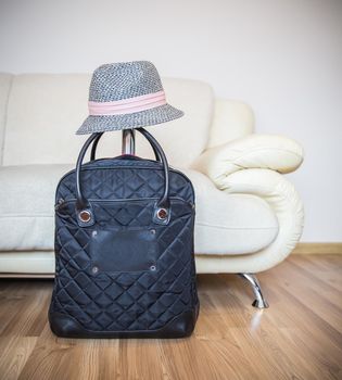 Suitcase and straw hat ready for travelling