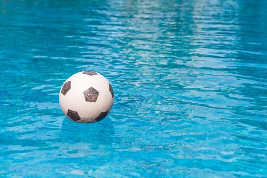 Inflatable football ball floating in the swimming pool