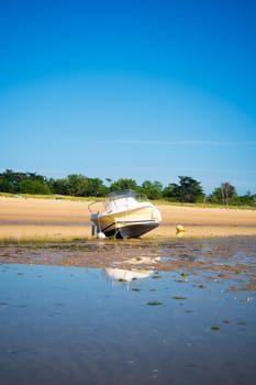 A motorboat laying on the beach plage de la loge at lowtide on a sunny summertime on the Isle of île de re in the Charente-Maritime in France