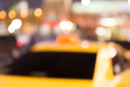 Busy city life blurred with taxi in foreground and street lights illuminating scene