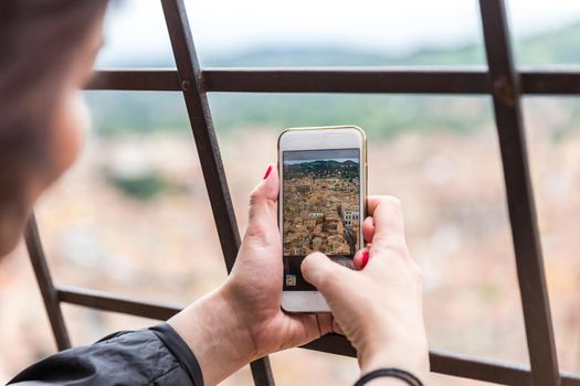 Taking picture of Bologna with cellphone from top of tower