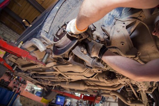 Gloved male hands install or remove the caliper on the wheel of an old car. In the garage, a man changes parts on a vehicle. Small business concept, car repair and maintenance service. UHD 4K.