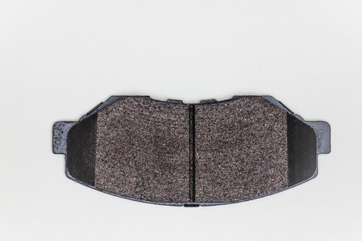 One brake pad on a flat surface. Set of spare parts for car brake repair. Details on white background, copy space available. UHD 4K.