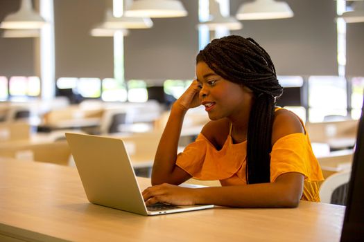 Young African American woman working using computer laptop concentrated and smiling.