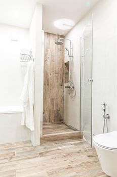 Walk in shower in bathroom with wooden style tile, glass door and hanging bathrobe