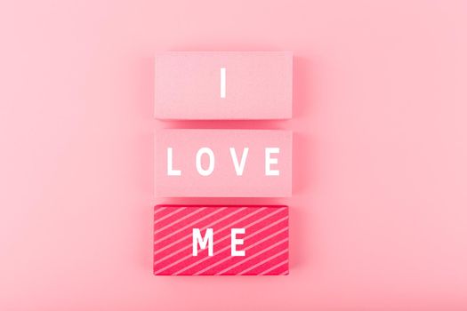 Trendy minimal I love me creative concept of self love and mental health or being single. Pink blocks with text against pink background with copy space