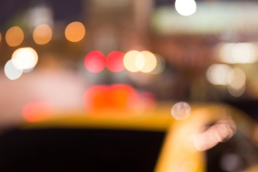 Busy city life blurred with taxi in foreground and street lights illuminating scene