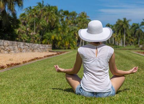 Woman doing yoga exercises in park sitting in lotus posture