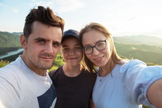 Selfie of family in mountain. Happy parents and happy child. Travel concept