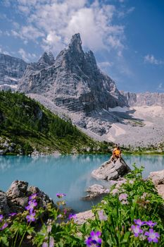 Morning with clear sky on Lago di Sorapis in the Italian Dolomites, milky blue lake Lago di Sorapis, Lake Sorapis, Dolomites, Italy. Couple man and woman mid age walking by the lake in the mountains 