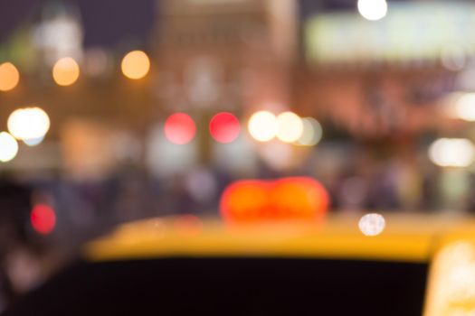 Busy city life blurred with taxi in foreground and street lights illuminating scene