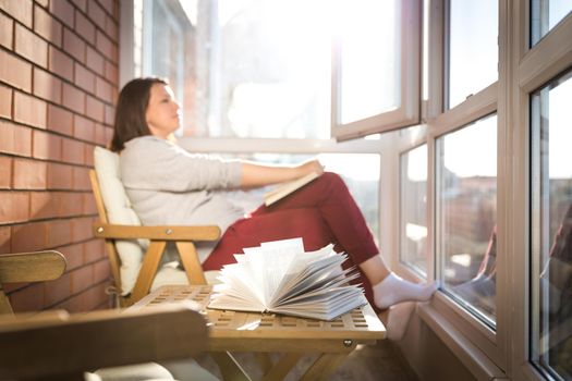 relaxed woman reading on balcony on a warm sunny day