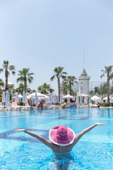 Woman in pink hat standing in a pool