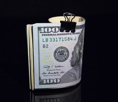 Ddollar bills rolled up with clip on black background