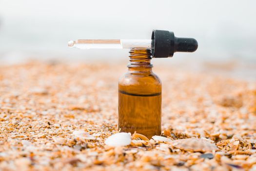 A bottle of cosmetic oil on the background of the sea . Cosmetic oil. Cosmetology. The sea wave. An oil based on algae. Copy Space