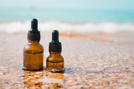 A bottle of cosmetic oil on the background of the sea . Cosmetic oil. Cosmetology. The sea wave. An oil based on algae. Copy Space