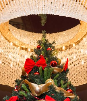 Tall christmas tree with round chandelier on a ceiling