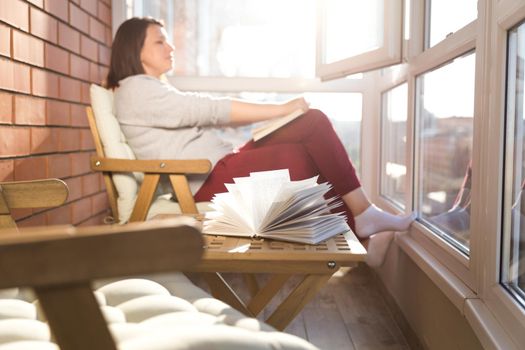 relaxed woman reading on balcony on a warm sunny day