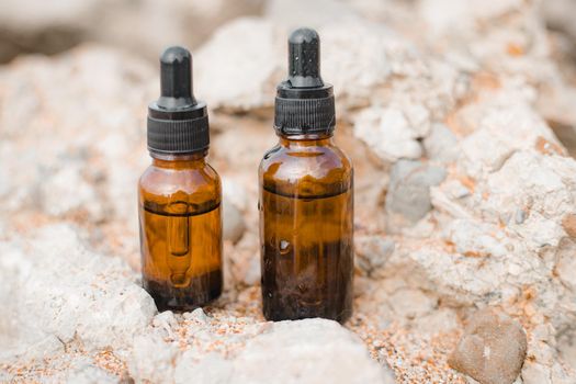 A bottle of cosmetic oil on a background of stones . Cosmetic oil. Cosmetology. Stones. An oil based on algae. Copy Space