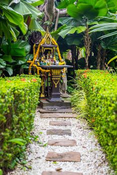 Traditional Thai spirit house with colorful garlands in Thailand